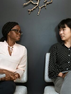 Two professional women engaging in a business discussion indoors.